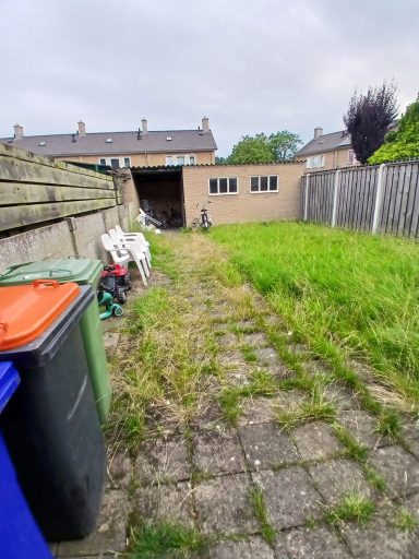 Tuinman verwijderen onkruid tussen stenen van oprit in Bergen op Zoom